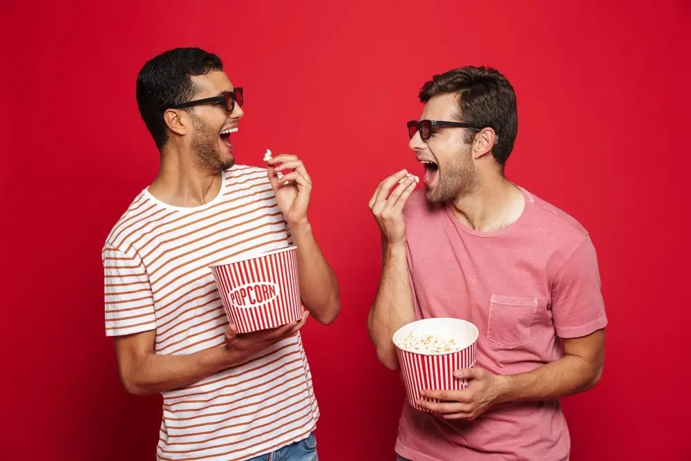 two cheerful young men standing isolated red wall eating popcorn wearing 3d glasses 171337 55854 ezgif.com resize